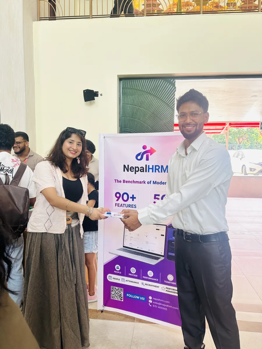 A NepalHRM team member presenting a prize to a visitor in front of the NepalHRM standee at Idea Summit 2026.