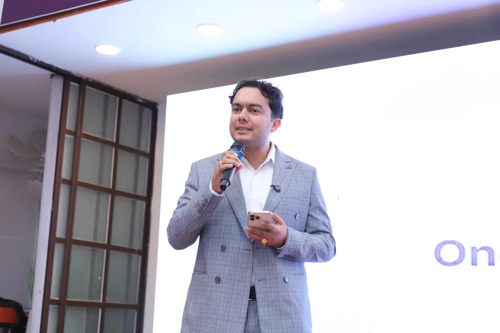 A NepalHRM presenter with a microphone opening the pitch on the Loop Arena stage at Nepal Fintech Expo 2026