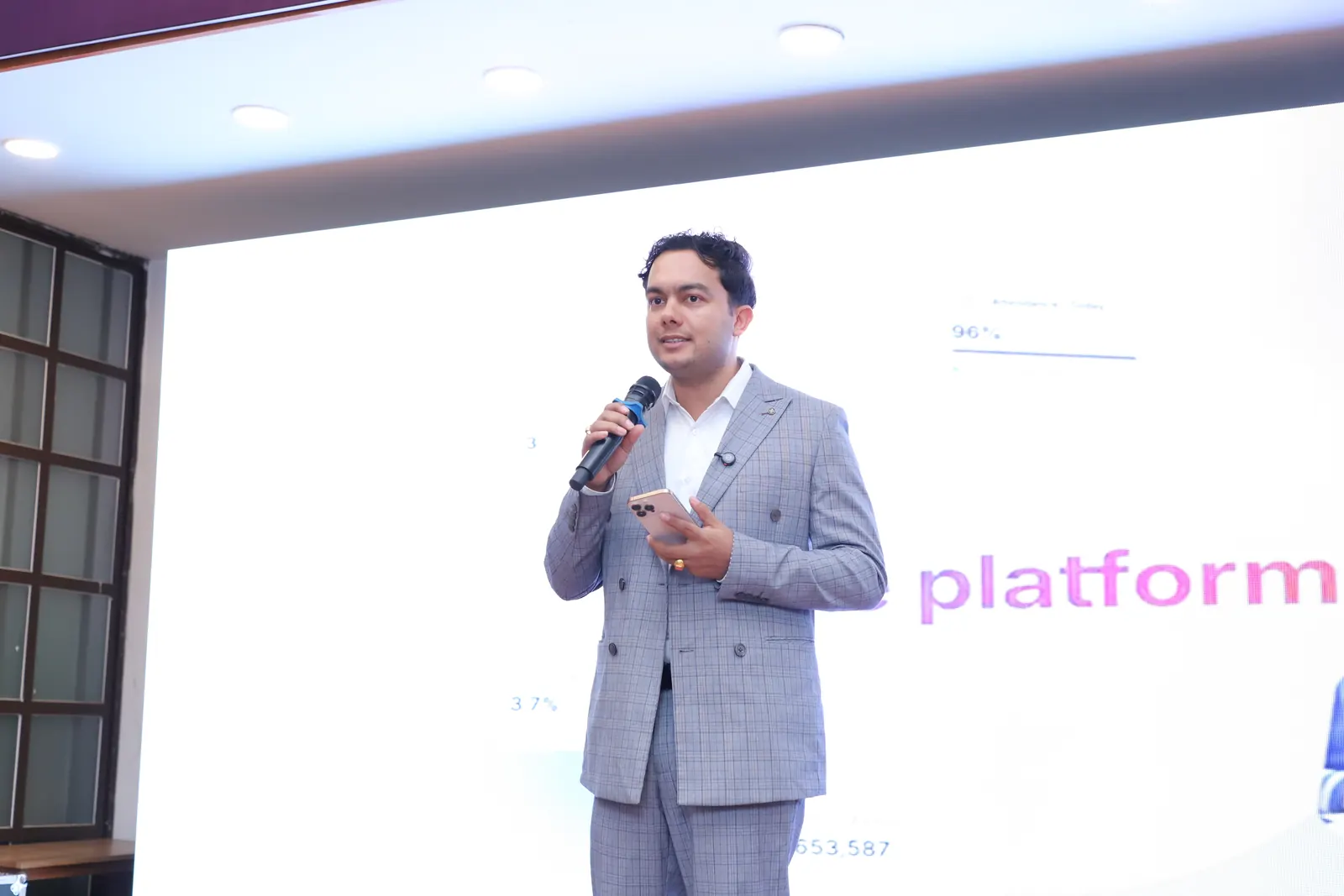 The NepalHRM presenter on the Loop Arena stage holding a microphone and a phone, with a slide about the platform behind them