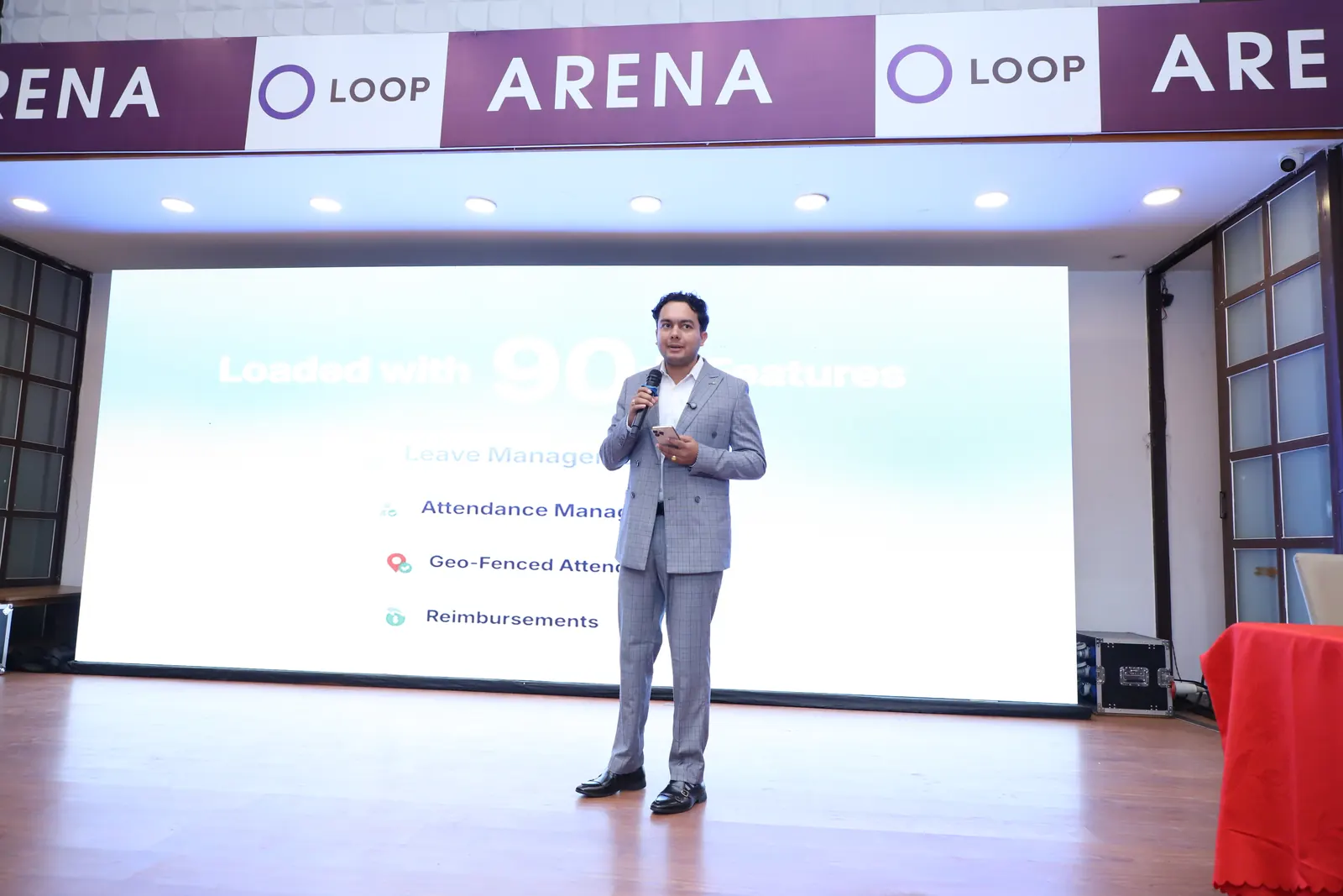 The NepalHRM presenter in front of a slide listing leave management, attendance management, geo-fenced attendance and reimbursements
