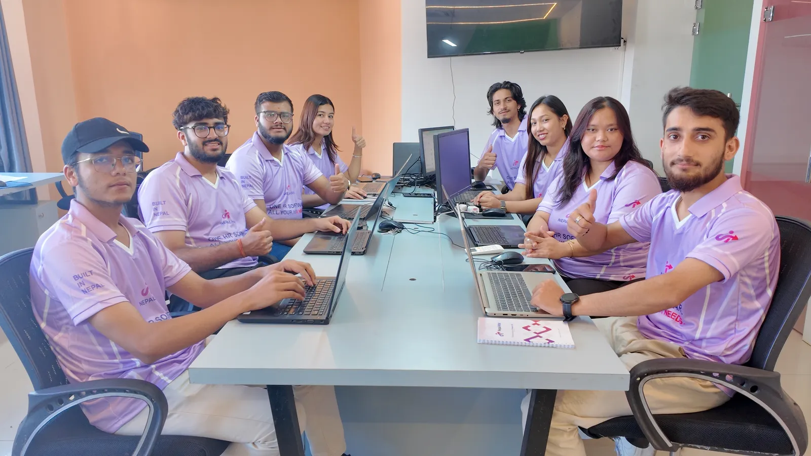 The NepalHRM team in matching lilac NepalHRM jerseys working on laptops around the meeting table at our Kathmandu office