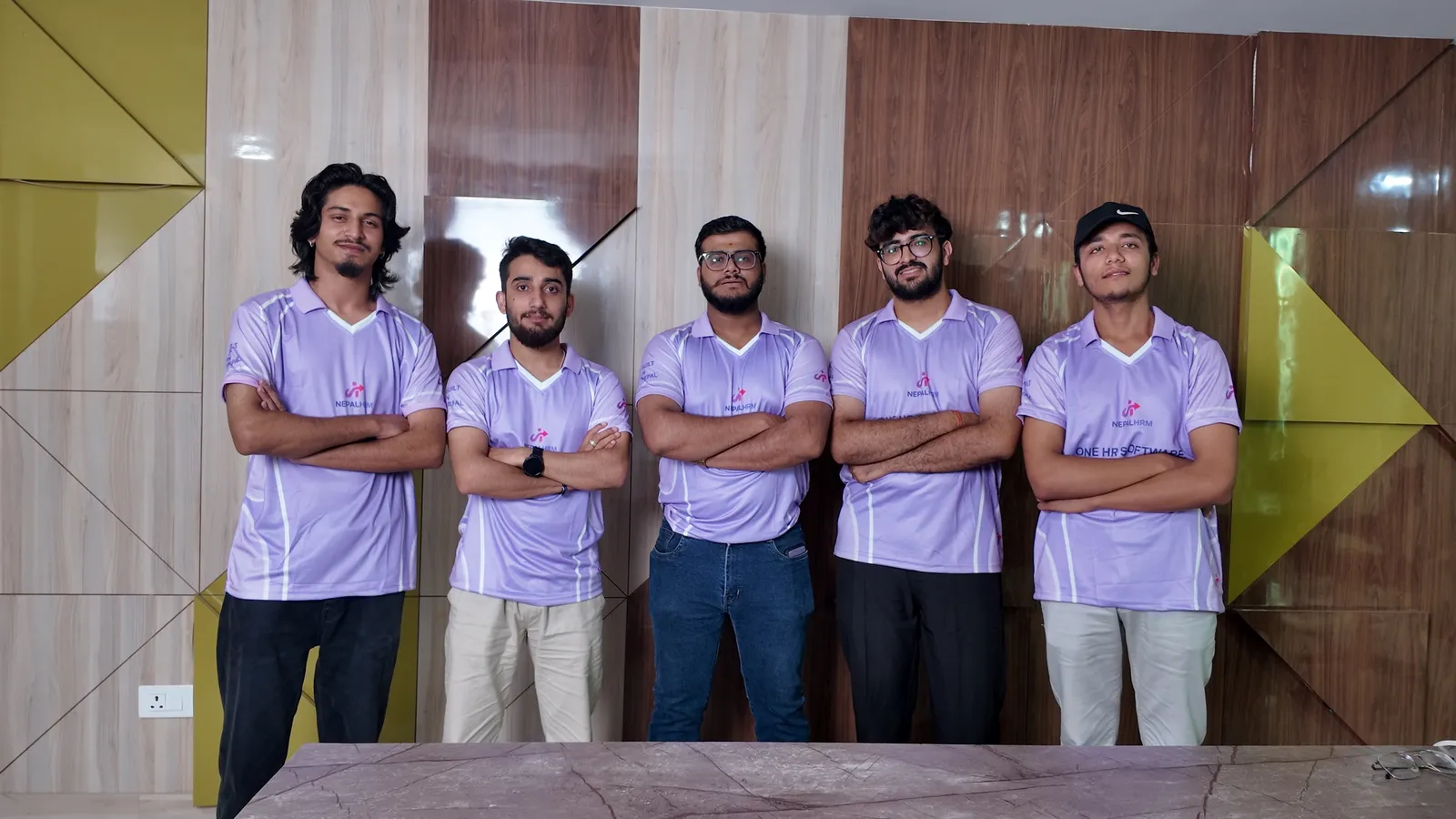 Five NepalHRM team members in NepalHRM jerseys standing with arms crossed in the meeting room at our Kathmandu office