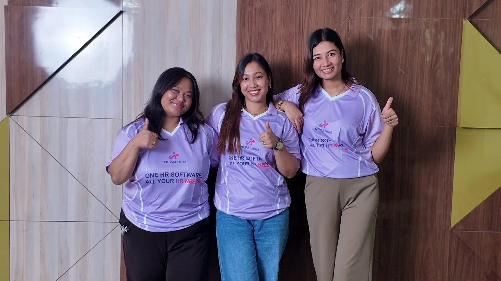 Three NepalHRM team members in NepalHRM jerseys smiling and giving a thumbs up at our Kathmandu office
